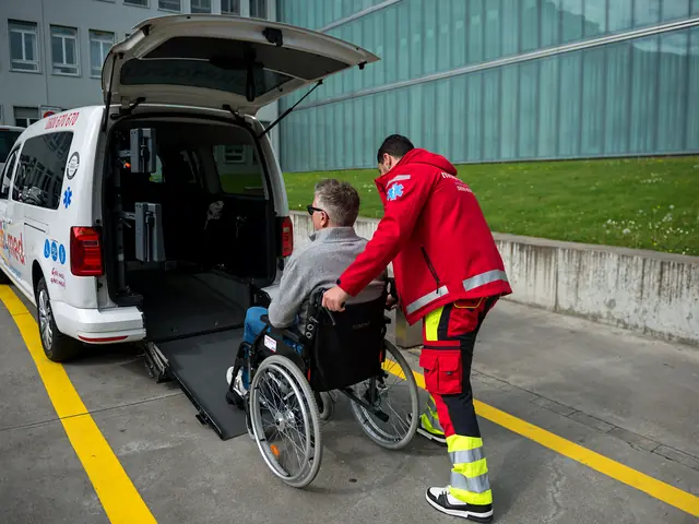 Mitarbeiter von Mobimed schiebt einen Patienten im Rollstuhl über die Rampe in ein Transportfahrzeug