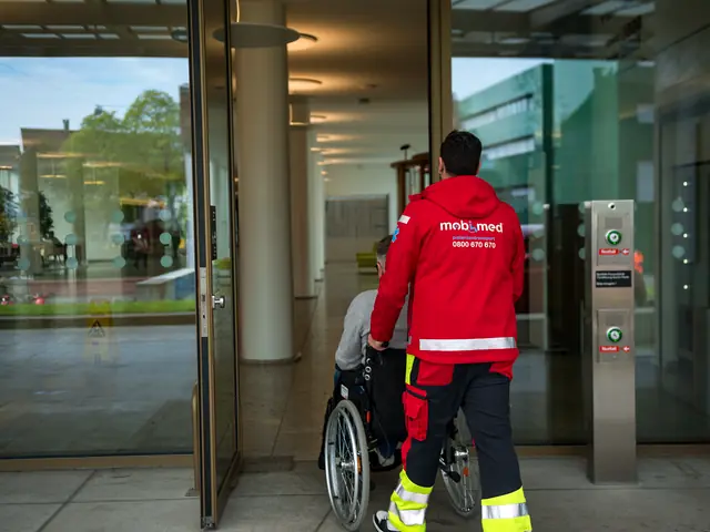 Mitarbeiter von Mobimed bringt einen Patienten im Rollstuhl durch die Eingangshalle eines Basler Spitals
