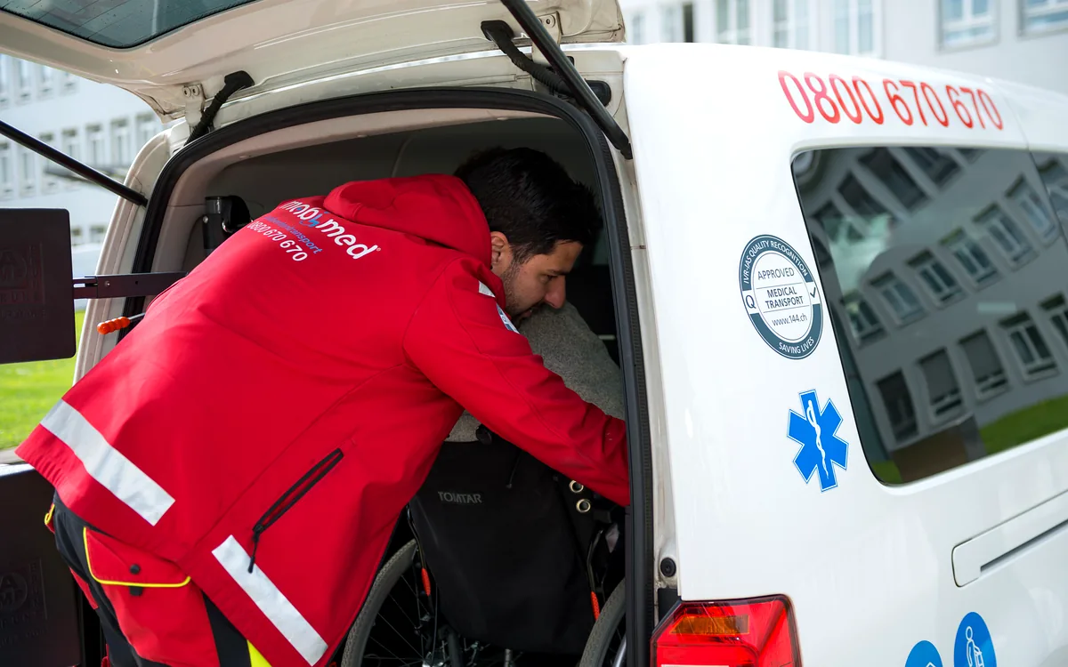 Mitarbeiter von Mobimed sichert einen Rollstuhl im Fahrzeug